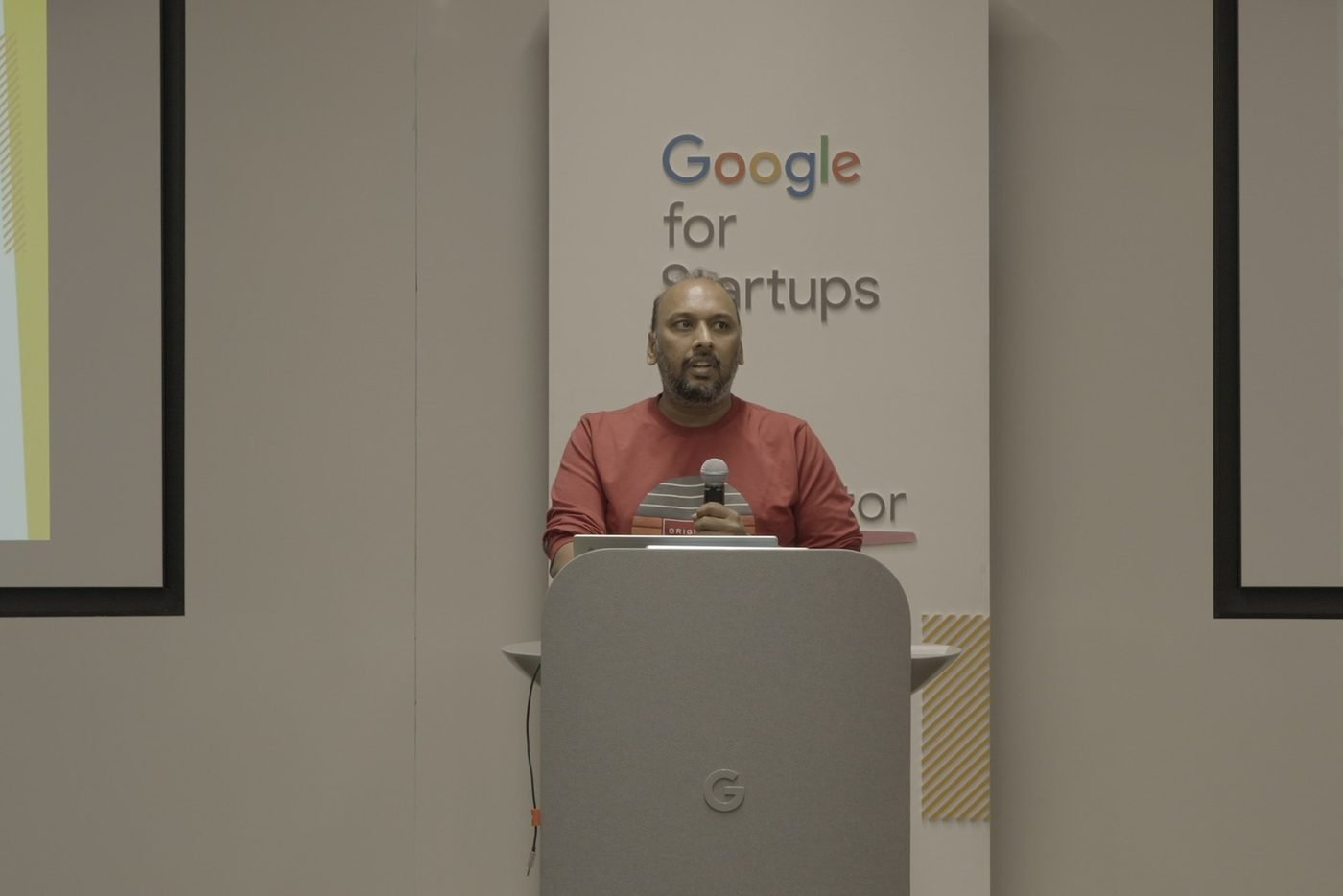 Naveen Budda presenting KarmaLife at a podium branded Google for Startups Accelerator.